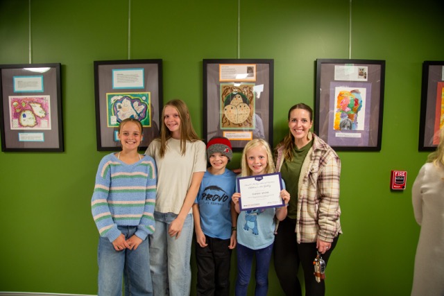 Family poses with child in front of artwork.