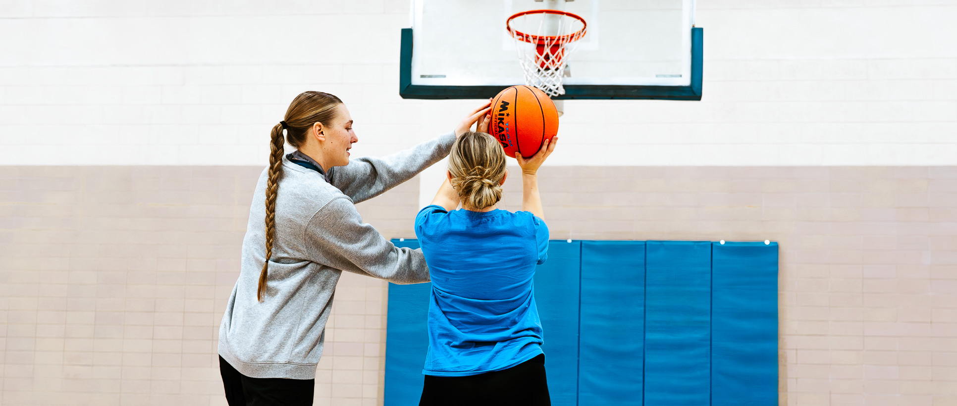 A girl learning basketball from her coach