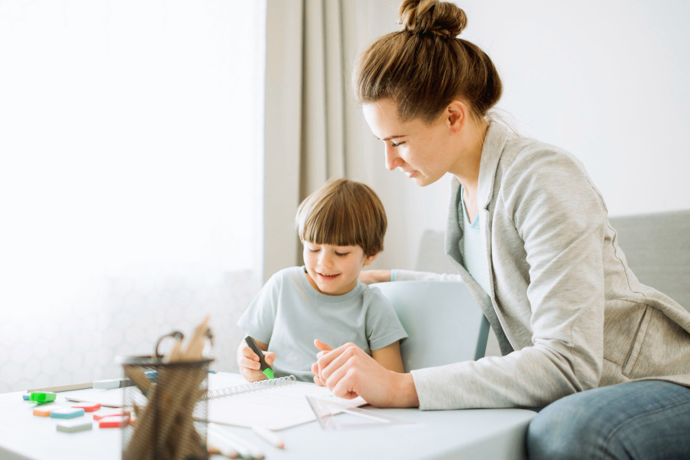 Woman helping child working in notebook