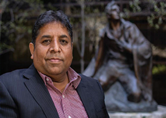 A photo of Patras Bukhari standing in front of a statue of Joseph Smith