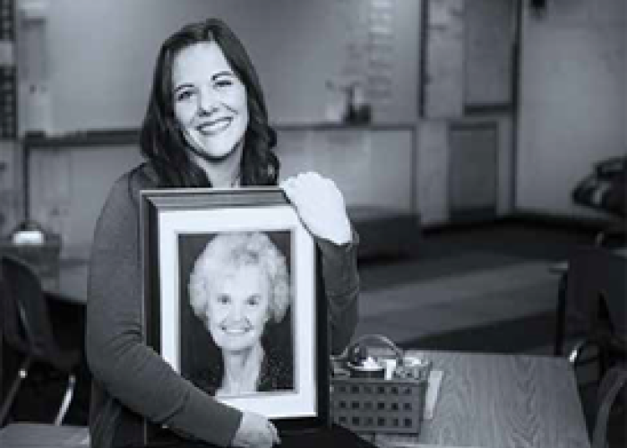 A woman holds a picture frame with a picture of an older woman.