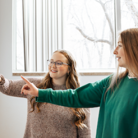 Two girls pointing at a wall